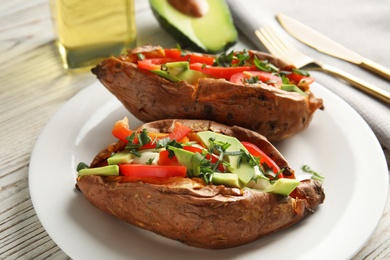 Photo of Plate with stuffed sweet potatoes on white wooden table, closeup