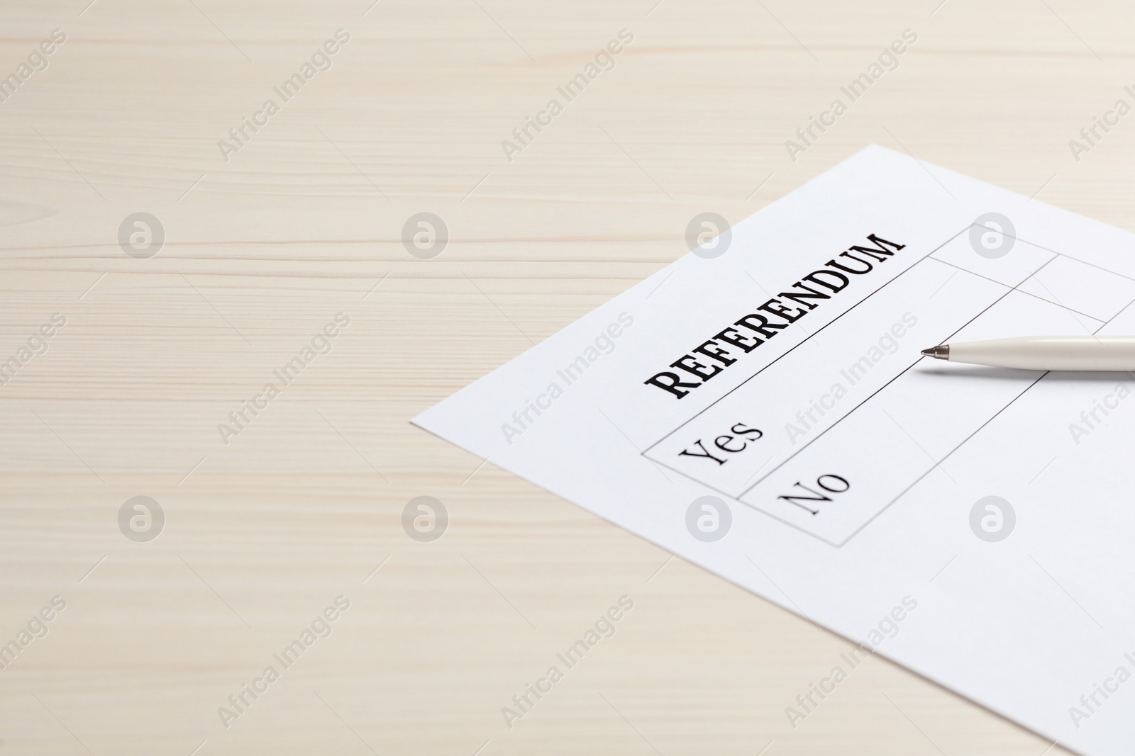 Photo of Referendum ballot with pen on white wooden table. Space for text