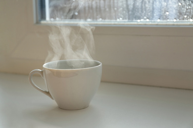 Photo of Cup of hot drink near window on rainy day.  Space for text