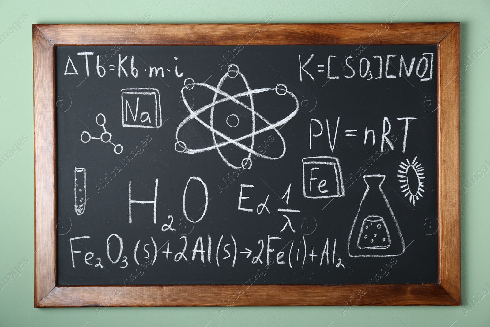 Photo of Blackboard with different chemical formulas written with chalk on light green wall