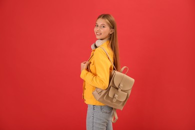 Photo of Teenage student with backpack and headphones on red background