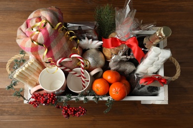 Crate with gift set and Christmas decor on wooden table, top view