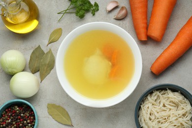 Photo of Delicious chicken bouillon and ingredients on light grey textured table, flat lay