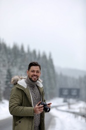 Male photographer with camera on snowy road. Winter vacation