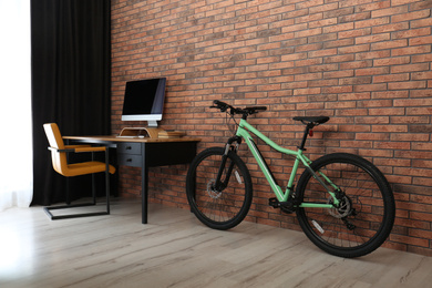 Photo of Stylish room interior with modern green bicycle and workplace