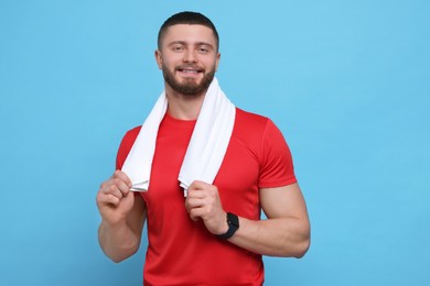 Handsome man with white towel on light blue background, space for text