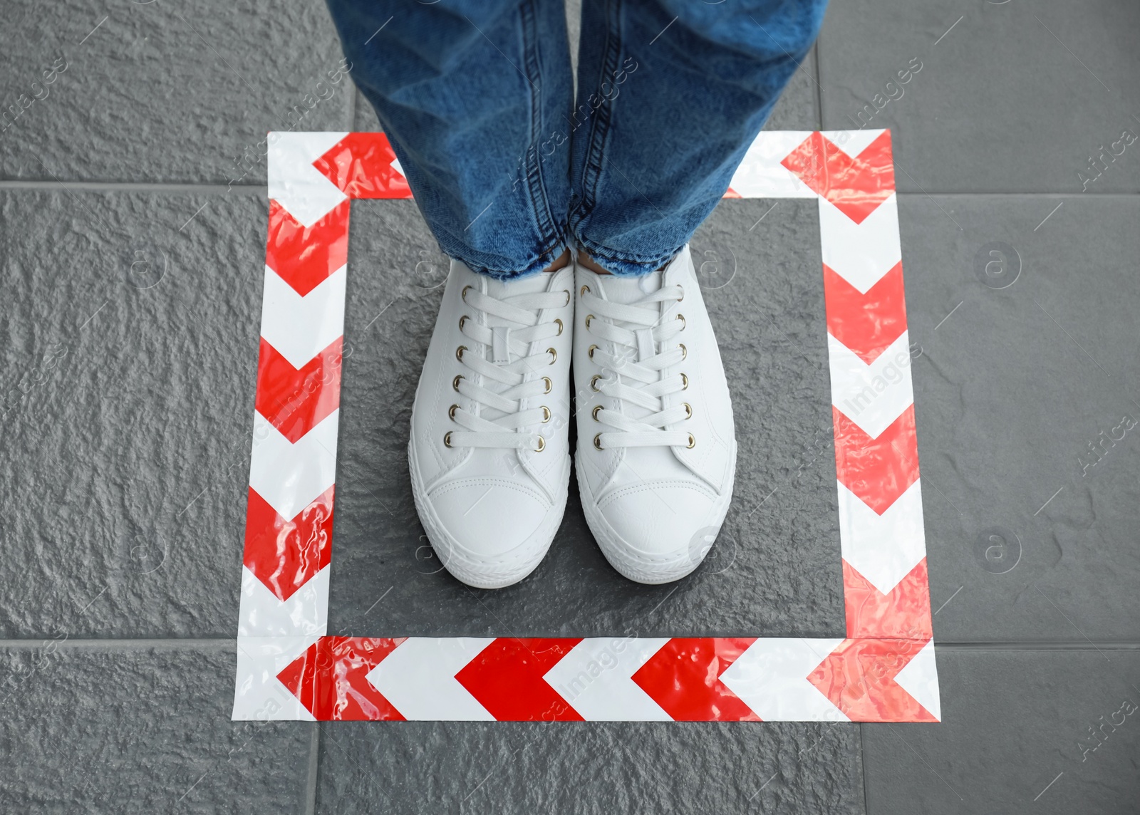 Photo of Woman standing on taped floor marking for social distance, top view. Coronavirus pandemic