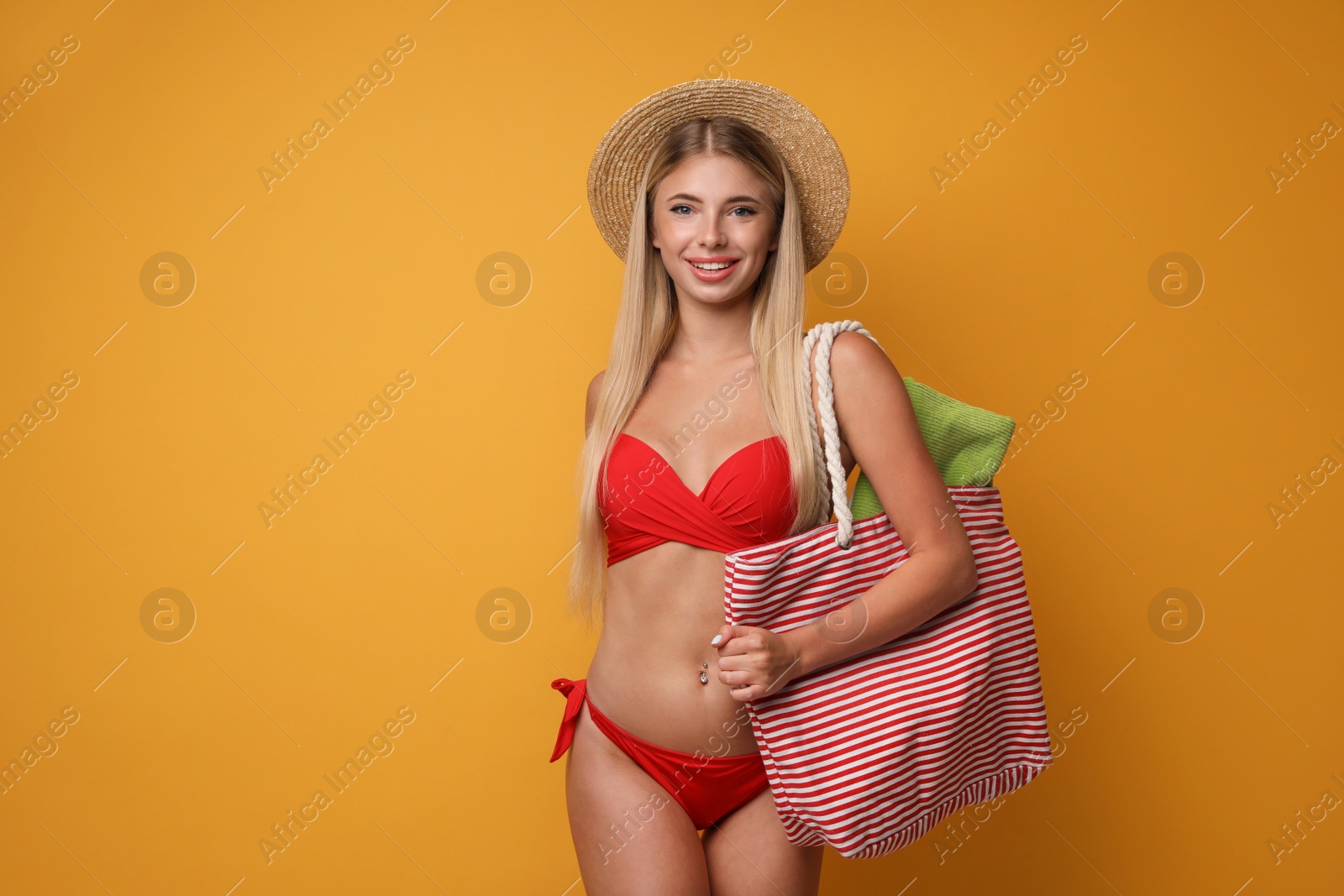 Photo of Pretty young woman wearing stylish bikini with bag on orange background