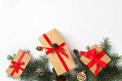 Photo of Christmas gift boxes and fir branches on white background, flat lay. Space for text