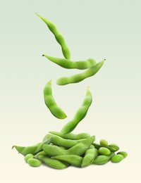 Image of Fresh edamame soybeans and pods falling onto pile against color background