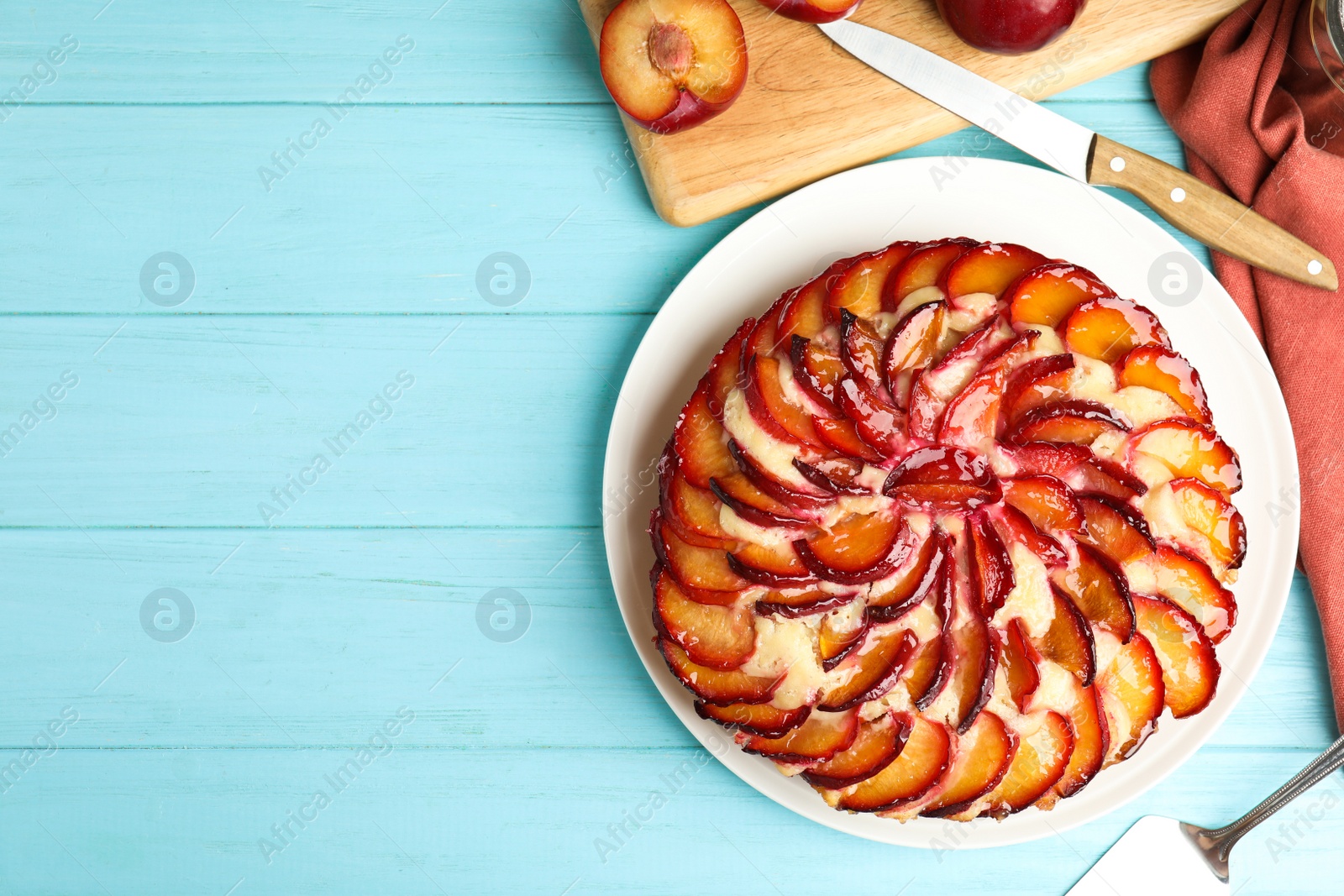 Photo of Delicious cake with plums on light blue wooden table, flat lay. Space for text