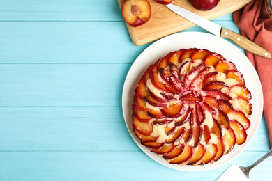 Photo of Delicious cake with plums on light blue wooden table, flat lay. Space for text