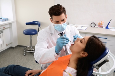 Photo of Professional dentist working with patient in clinic
