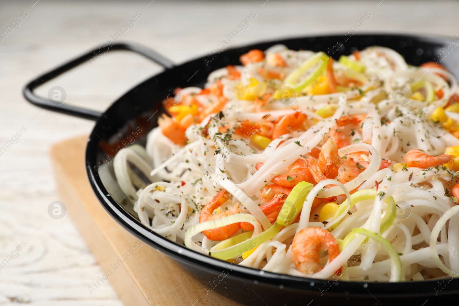 Photo of Frying pan with rice noodles, shrimps and vegetables on table