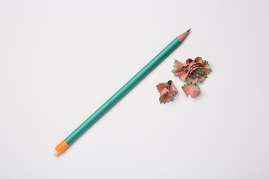Photo of Graphite pencil and shavings on white background, flat lay