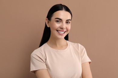 Beautiful woman with clean teeth smiling on beige background