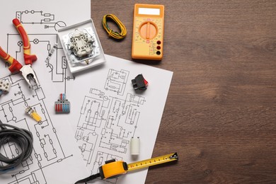 Photo of Flat lay composition with wiring diagrams and digital multimeter on wooden table, space for text