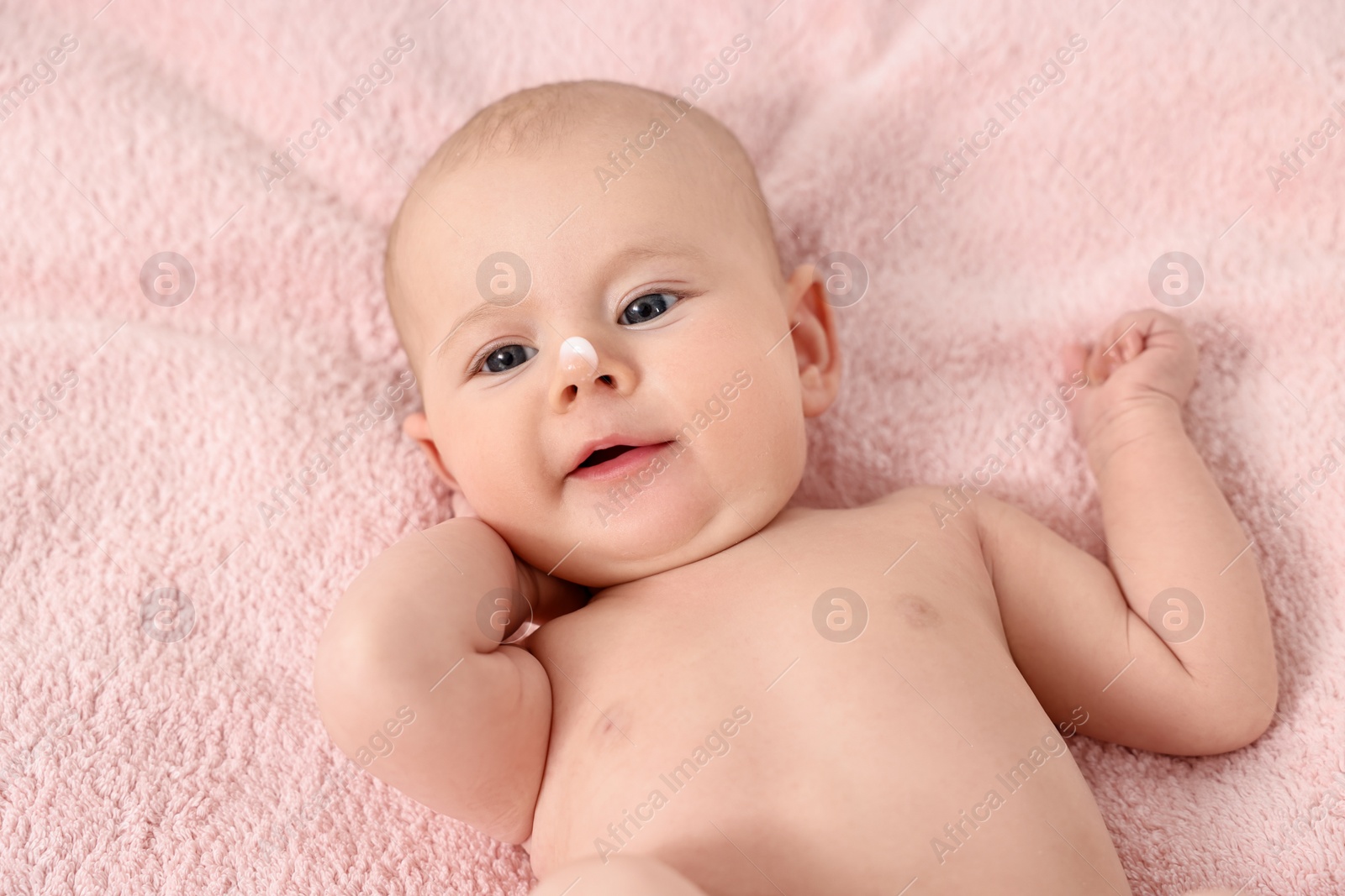 Photo of Cute little baby with cream on nose on pink blanket, above view