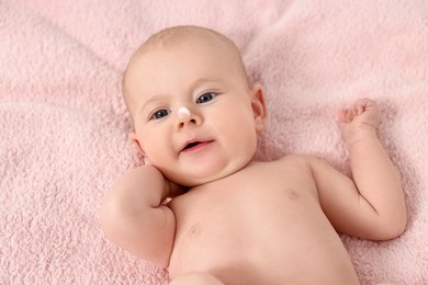 Photo of Cute little baby with cream on nose on pink blanket, above view