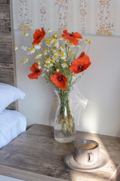 Photo of Bouquet of beautiful wildflowers and cup with coffee on nightstand in bedroom