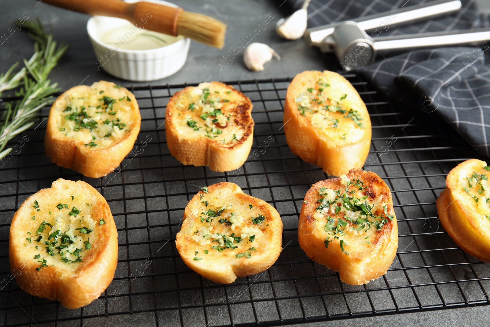 Photo of Baking rack with tasty homemade garlic bread on table