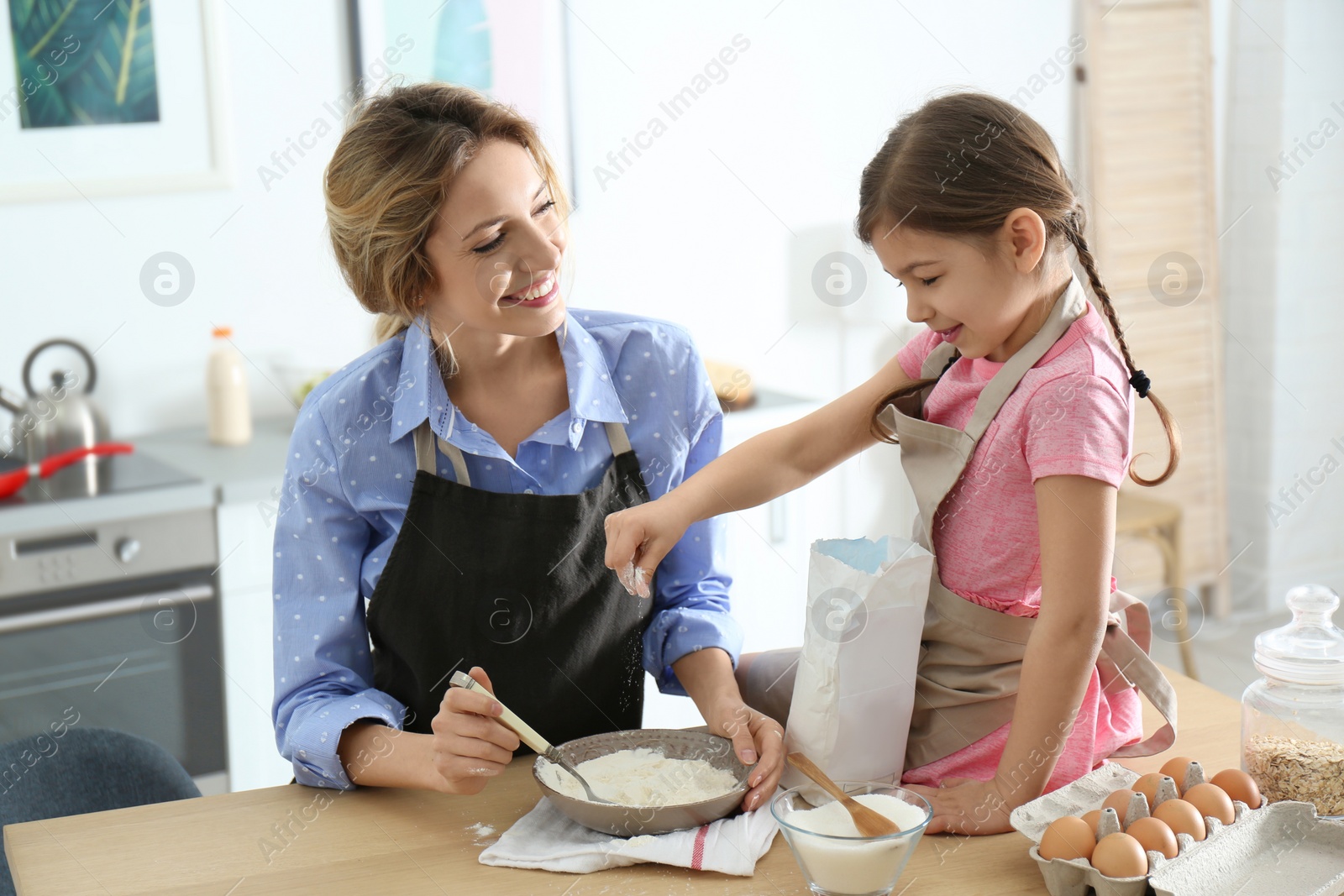 Photo of Young nanny with cute little girl cooking together in kitchen