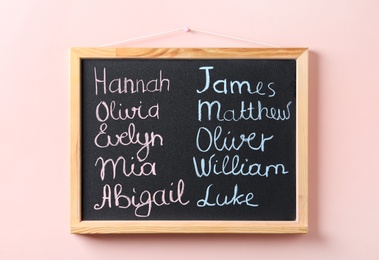 Photo of Blackboard with baby names hanging on pink wall