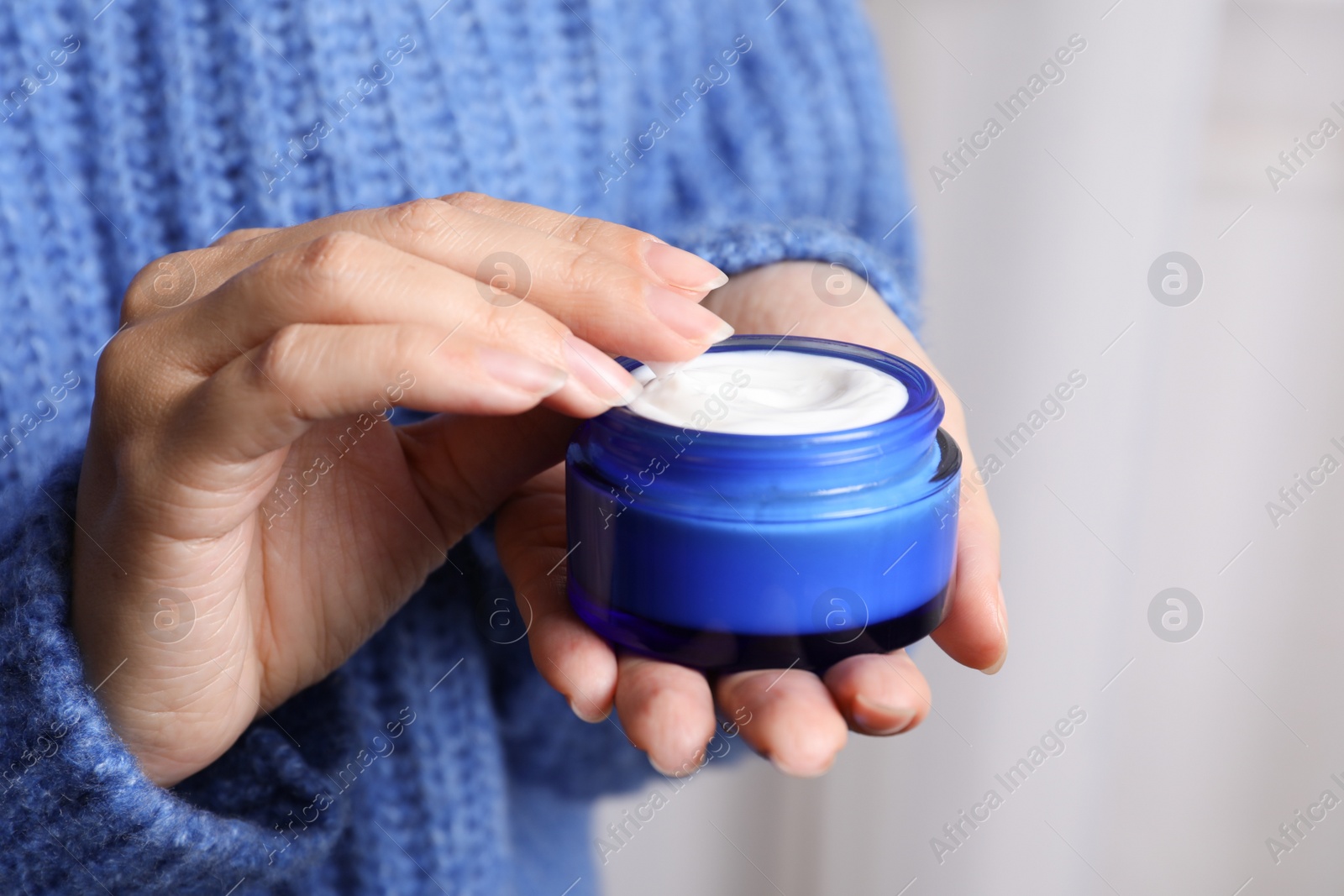 Photo of Woman holding jar of moisturizing cream, closeup. Winter skin care cosmetic