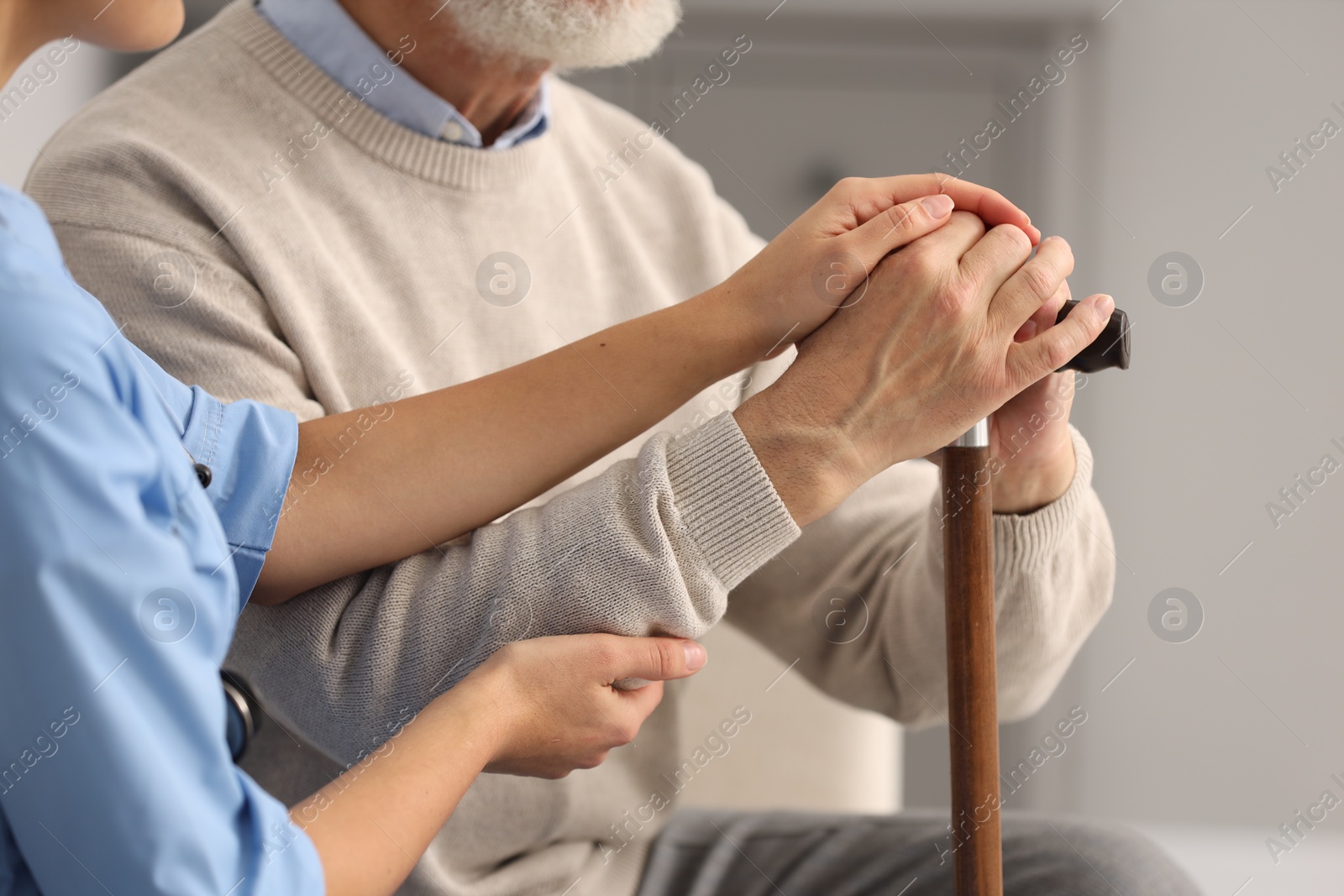 Photo of Nurse supporting elderly patient indoors, closeup view