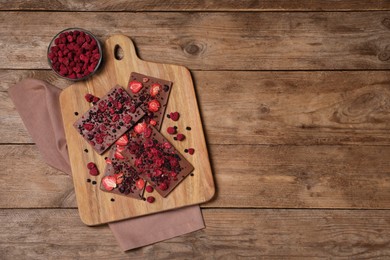 Chocolate bars with freeze dried fruits on wooden table, flat lay. Space for text