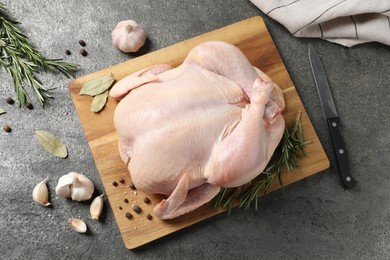 Photo of Fresh raw chicken with spices and knife on grey textured table, flat lay