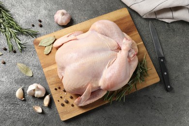 Fresh raw chicken with spices and knife on grey textured table, flat lay