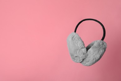 Stylish winter earmuffs on pink background, space for text