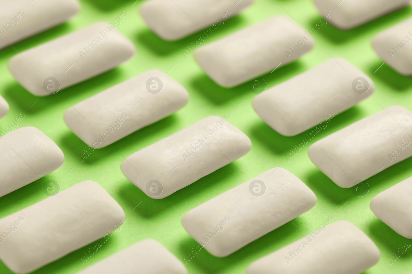 Photo of Many chewing gum pieces on green background, closeup