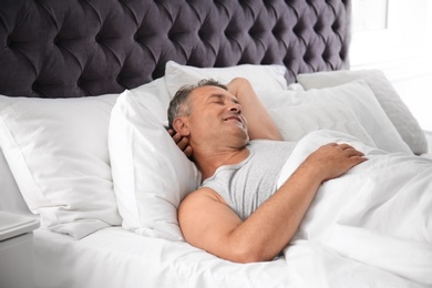 Man sleeping on comfortable pillow in bed at home