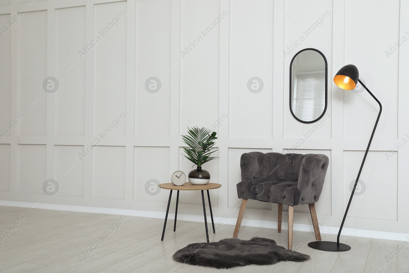 Photo of Simple room interior with comfortable armchair, decor elements and empty wall. Space for design