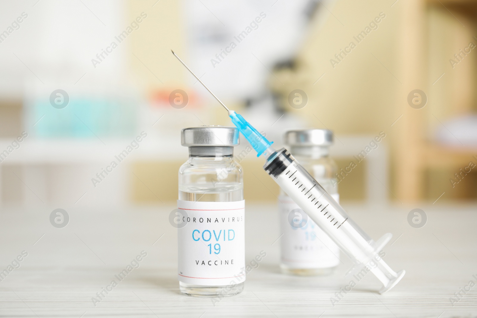 Photo of Vials with vaccine against Covid-19 and syringe on white table indoors