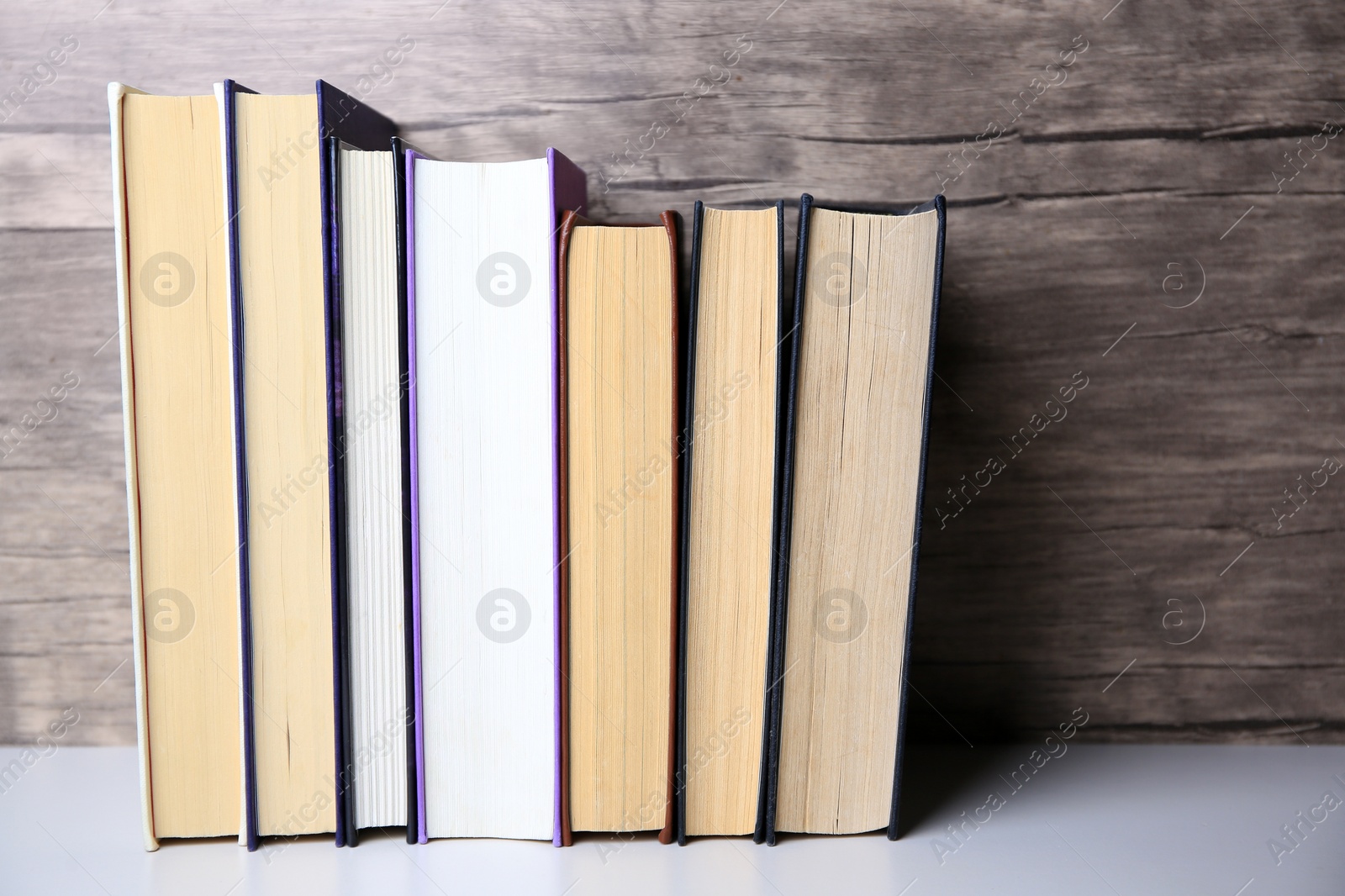 Photo of Collection of different books on white shelf, space for text