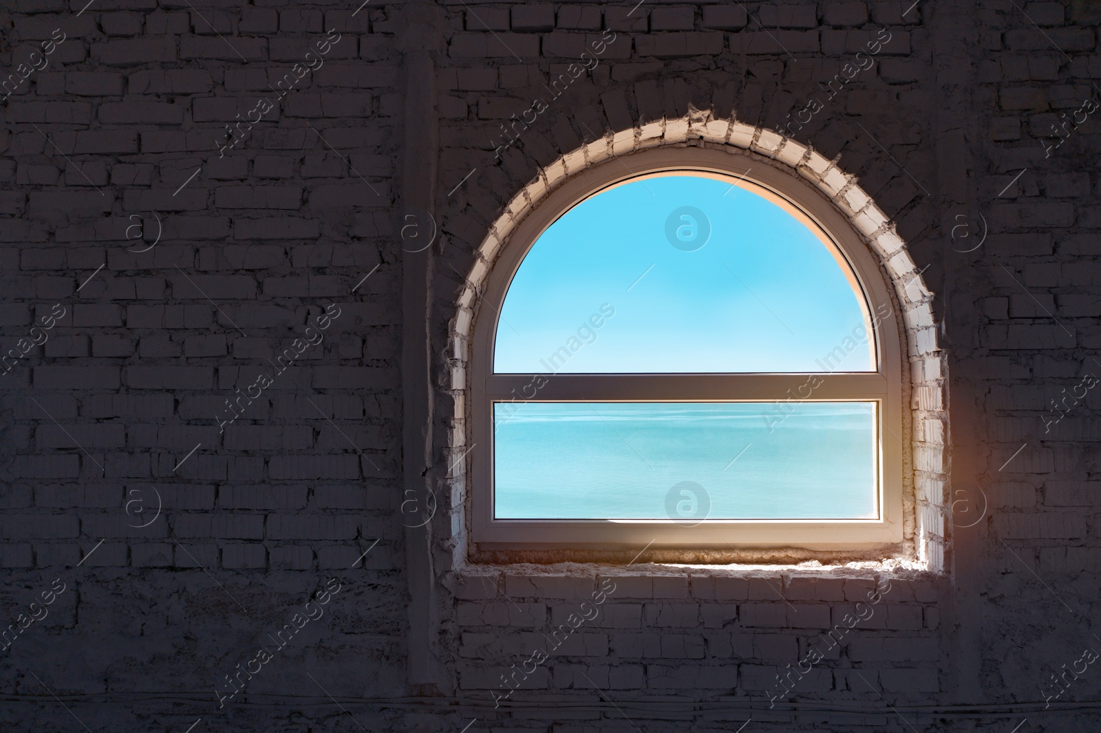 Image of Beautiful sky and sea visible through old window in brick wall 