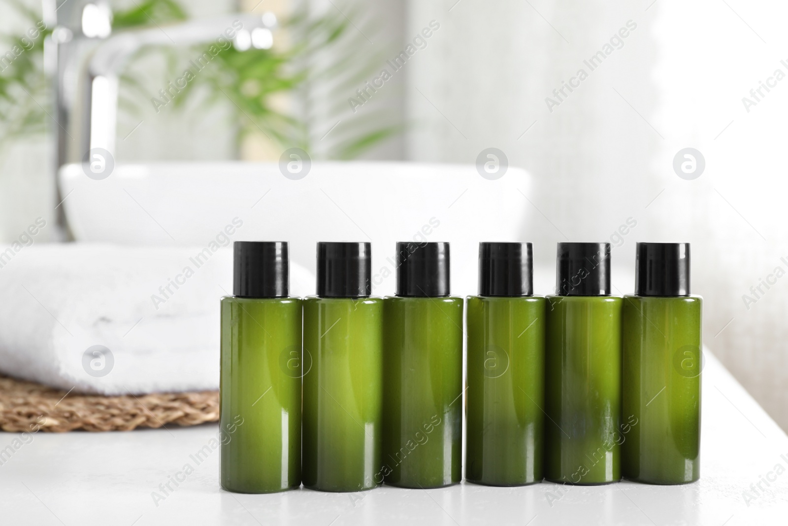 Photo of Mini bottles with cosmetic products on white table in bathroom