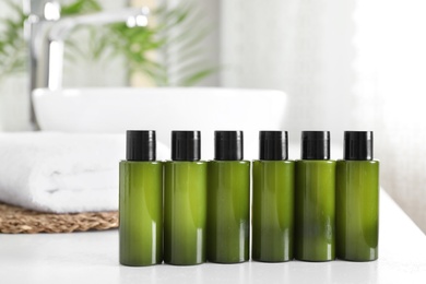 Mini bottles with cosmetic products on white table in bathroom