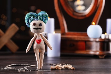 Photo of Female voodoo doll with pins in heart and ceremonial items on wooden table, space for text