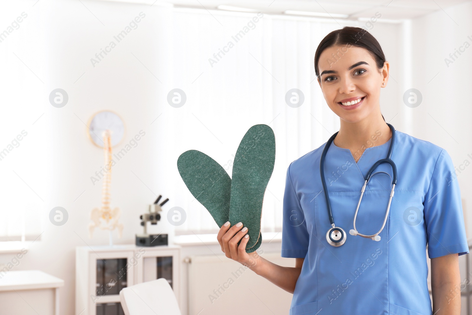 Photo of Young female orthopedist showing insoles in clinic