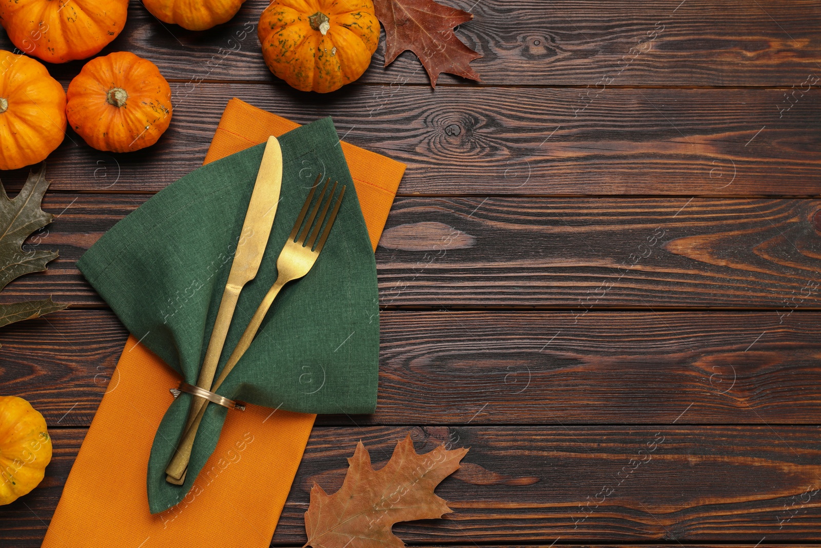 Photo of Cutlery, napkins and autumn decoration on wooden background, flat lay with space for text. Table setting