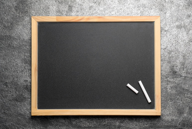 Photo of Empty blackboard with chalk on grey stone background, top view. Space for text