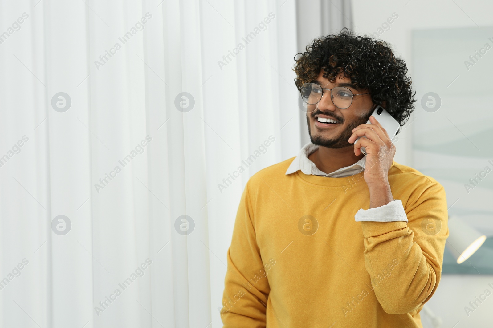 Photo of Handsome smiling man taking over smartphone indoors, space for text