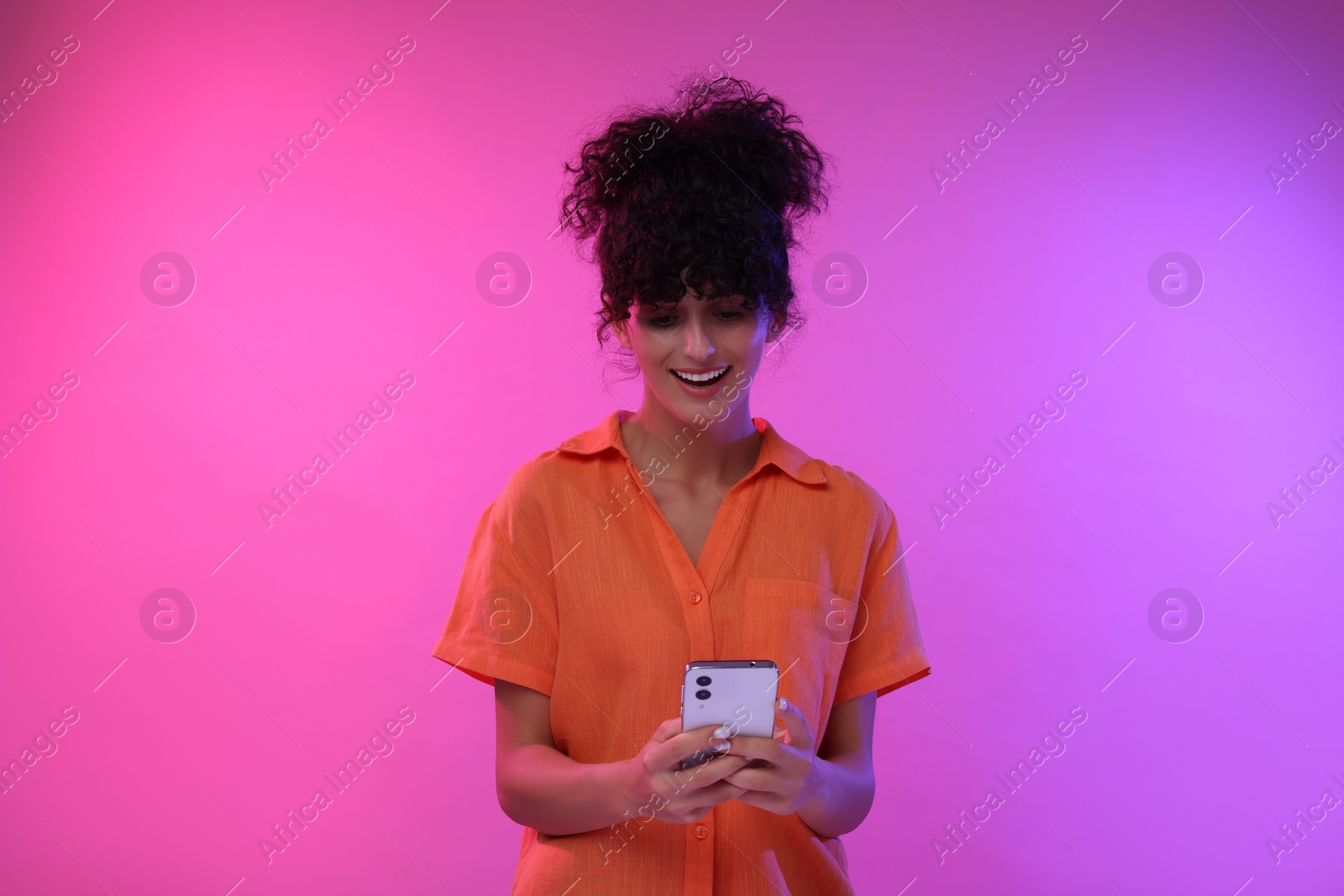 Photo of Woman sending message via smartphone on color background