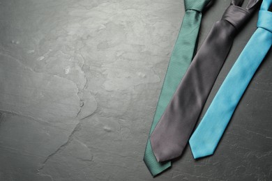Photo of Different neckties on grey textured table, flat lay. Space for text