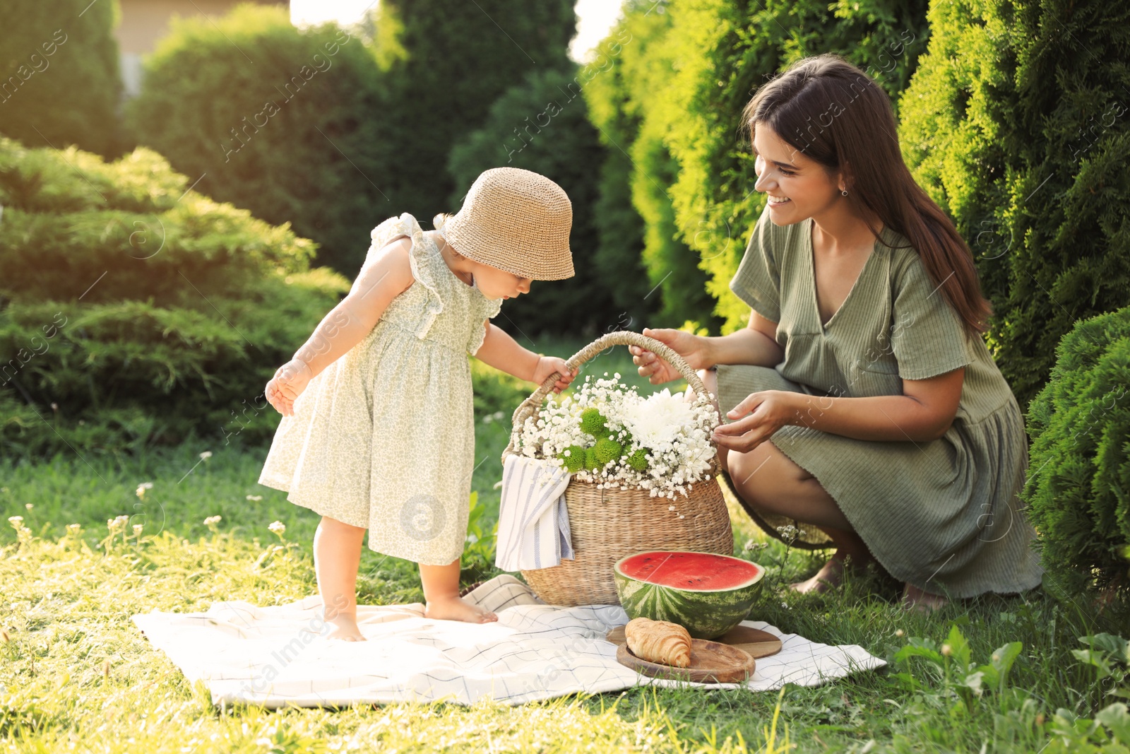 Photo of Mother with her baby daughter having picnic in garden on sunny day