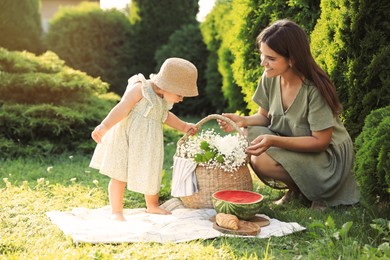 Mother with her baby daughter having picnic in garden on sunny day